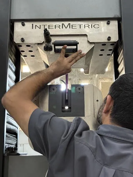 Técnico preparando corpo de prova em máquina universal de ensaio de tração
