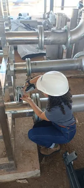 Técnica realizando PMI em tubulação industrial, em campo